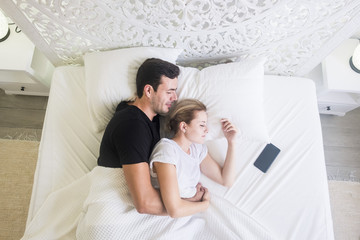 Obraz na płótnie Canvas aerial view of beautiful caucasian young beautiful couple sleeping at home in a white bed in the bedroom. stylish home and pretty people resting together with love and protection. happy moning