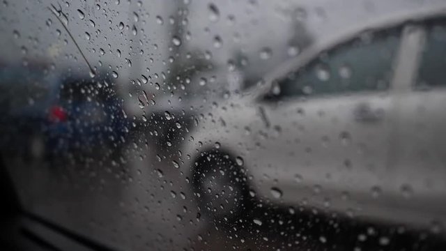 slow motion, rain drops on window with car stopped on road traffic jam
