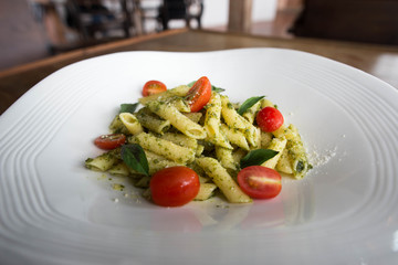 Pasta with tomato sauce and basil in white dish on wooden background. Italian food for vegetarian and healthy.
