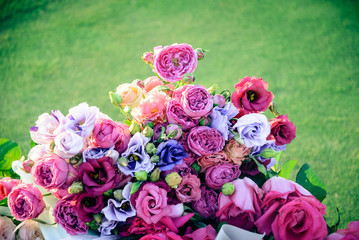 Bouquet of assorted beautiful roses in green grass background during sunset