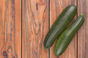 Squash, zucchini black beauty organic. Top view. Brown wooden desk background.