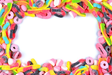 Frame of assorted gummy candies isolated on white. Top view. Space for text or design.