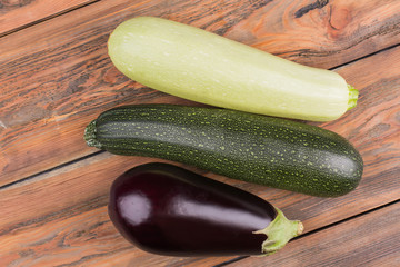 Ripe fresh raw vegetables. Top view. Courgette, zucchini and eggplant. Wooden desk background.