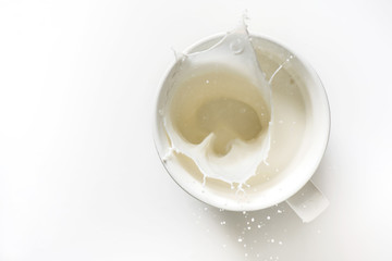 top view of milk splash out of glass isolated on white background - obrazy, fototapety, plakaty