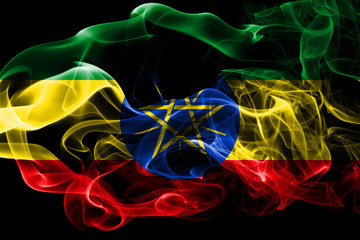 Fototapeta premium National flag of Ethiopia made from colored smoke isolated on black background. Abstract silky wave background.