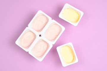 Plastic cup with tasty yogurt on lilac background. Top view. Space for text or design.