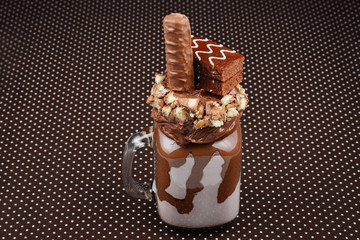 Chocolate extreme milkshake with brownie cake, chocolate paste and sweets. Crazy freakshake food trend. Copy space