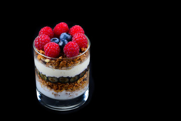 Healthy blueberry and raspberry parfait in a glass on a black background. Two portions. Space for text or design.