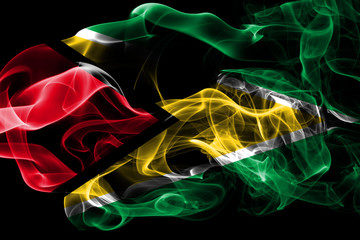 National flag of Guyana made from colored smoke isolated on black background. Abstract silky wave background.