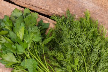 Bunches of dill and parsley. Cooking fresh salad, wooden table background.