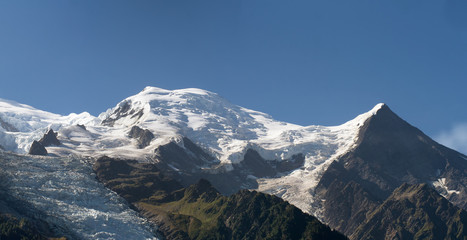 Dome and Aiguille du Gouter mountain peaks with the Bossons Glacier in the European Alps, a summer snowy landscape.