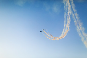 Unidentifiable airplanes performing acrobatic flight on blue sky. Trace of Smoke behind