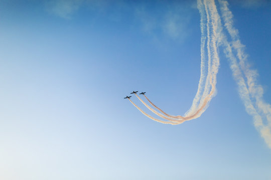 Unidentifiable airplanes performing acrobatic flight on blue sky. Trace of Smoke behind