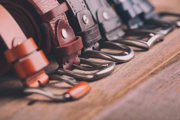 Foto op Plexiglas Leather belts on a wooden background. Fashionable leather belts. © fortton