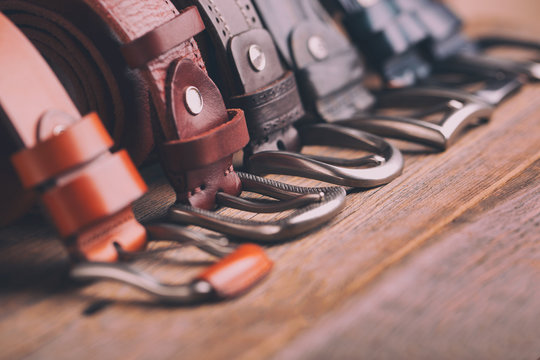 Leather belts on a wooden background. Fashionable leather belts.