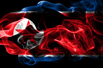 Fototapeta premium National flag of North Korea made from colored smoke isolated on black background. Abstract silky wave background.