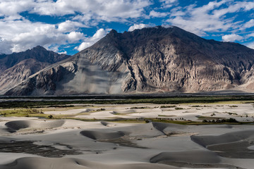 Sand Dune of Nubra Valley with mountains in background and cloudy blue sky in summer of Leh Ladakh, Jammu and Kashmir, India © jiradet_ponari