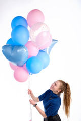 Fototapeta na wymiar Attractive caucasian redhead girl in blue sweater smiling and holding in greetings manner pink and blue balloons, isolated