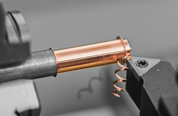 Detail of tool bit when working on a lathe. Close-up of bronze workpiece clamped in black and white...
