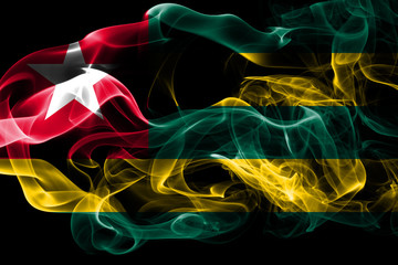 National flag of Togo made from colored smoke isolated on black background. Abstract silky wave background.
