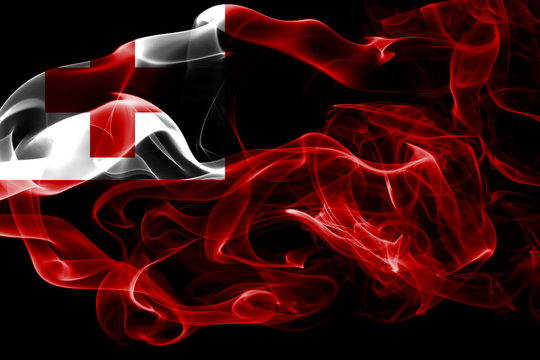 National flag of Tonga made from colored smoke isolated on black background. Abstract silky wave background.