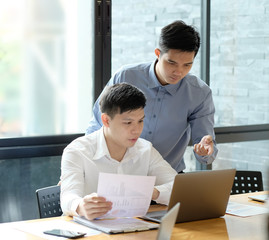 Business partner talking and consult with laptop computer and paper document.