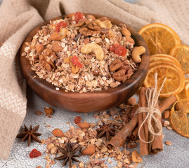 Wooden Bowl with granola with nuts, dried cranberries and dried orange on a old light table