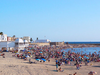 gente tomando el sol al atardecer en la playa de la Caleta en la bahia de Cádiz, Andalucía. España. Europa.