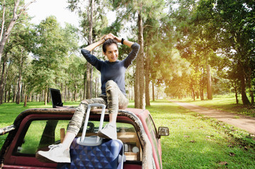 Woman relaxing on the car roof in her spring road trip, carefree and enjoying freedom and travel. travel concept scene.