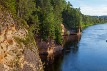 Fototapeta na wymiar Peaceful landscape with Gauja river and red sandstone (Erglu klint) steep rocks in Gauja National Park in Valmiera area