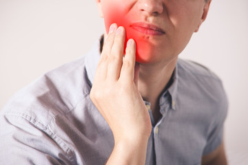 Man suffering from a toothache on gray background