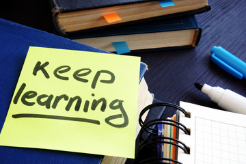 Lifelong learning concept. Book and piece of paper with words keep learning.