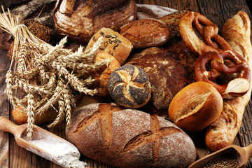 Different kinds of bread and bread rolls on board from above. Kitchen or bakery