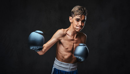Handsome shirtless young boxer during boxing exercises, focused on process with serious concentrated facial.
