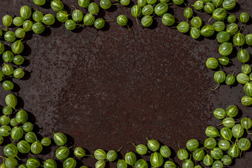 Rusty metal surface dark background with some fresh gooseberry, empty space