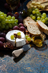 snacks, fruit and Camembert cheese and dark background