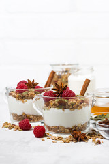 spicy dessert with sweet granola and yogurt in the glass on white background, vertical