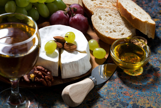 snacks, glass of wine and Camembert cheese on a dark background, closeup