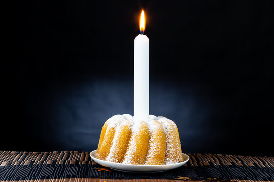 Kuchen mit Puderzucker und Kerze als Geburtstagskuchen für Kaffestunde bei Kerzenschein