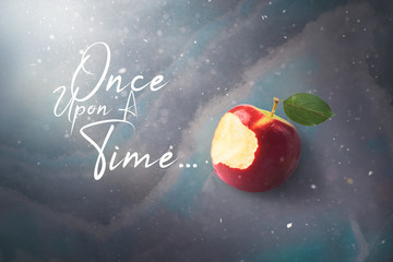 Fairy tale tale concept with poisoned bitten red apple laying on marble
