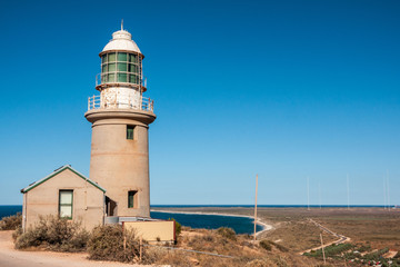 Fototapeta na wymiar Exmouth, Western Australia - November 27, 2009: Vlaming Head Lighthouse overlooking Indian Ocean against deep blue sky. Antennas of naval base on horizon.