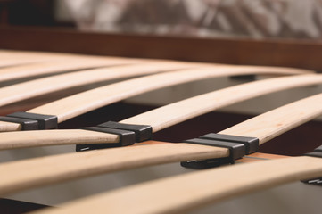 Close-up wooden elements of an arthopedic base of a double bed. Interior structure of furniture