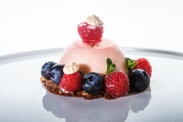 closeup pink dessert covered with fresh raspberry and blueberry