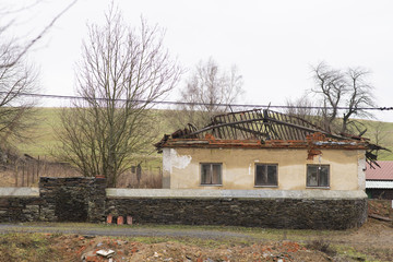 Abondoned and uninhabitable house with damaged roof without tiles. Depressive winter countryside view. House with no owner