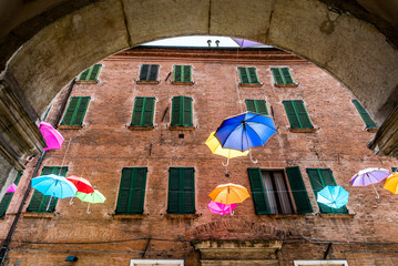 bunte Schirme vor einem traditionellen Haus mit grünen Fensterläden in Ferrara, Italien