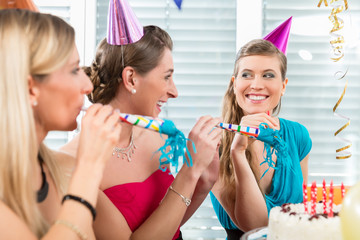 Portrait of a happy and beautiful young woman celebrating her birthday with her best female friends in a decorated room at home