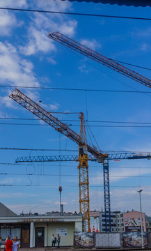 An image of two construction cranes silhouetted against a sky on a city centre building site