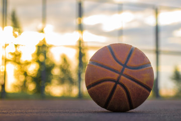 Basketball ball lies on the ground against the background of the evening sky. Sports background