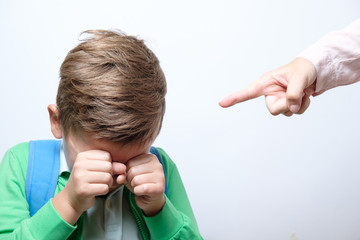 Hand of a strict teacher and scared schoolboy with blue backpack on a white background. punishment concept