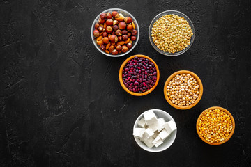 Products rich protein. Legumes, nuts, low-fat cheese. Raw beans, chickpeas, lentil, almond, hazelnut on black background top view space for text